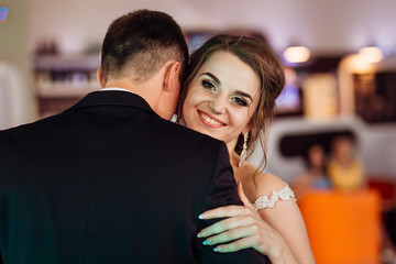 Joyful bride looks over groom's shoulder while dancing in the re