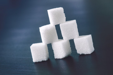 Cubes of sugar on a dark background. Unhealthy ingredients. Lump sugar