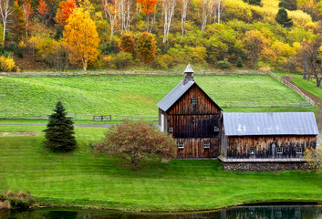 Fototapeta premium Beautiful old barn in a green meadow and colorful autumn trees
