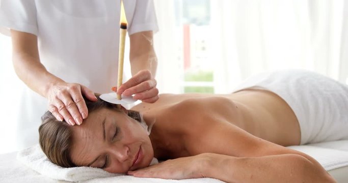 Therapist ear candling her patient