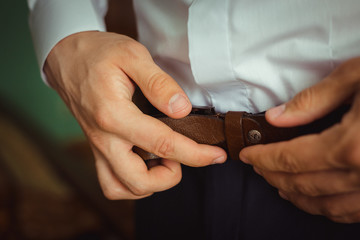 Man adjusts belt on the blue trousers