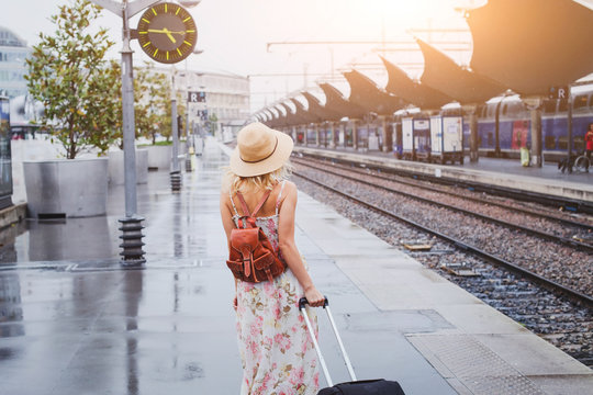 travel by train, woman with luggage waiting on platform of railway station