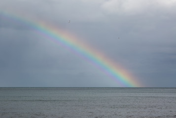 Rainbow over the sea with storm clouds