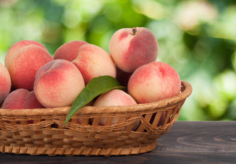 peaches in a wicker basket on  wooden table with  blurred background