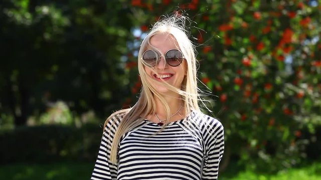 Young beautiful blonde woman in a striped blouse, summer outdoors