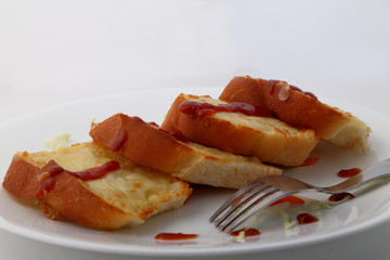 Garlic and herb bread slices with tomato sauce in white plate.
