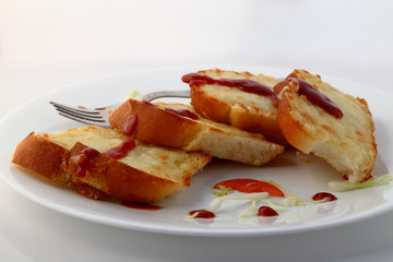 Garlic and herb bread slices with tomato sauce in white plate.