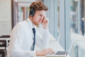 businessman in headphones working with laptop in modern cafe interior