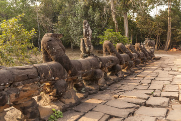Fototapeta premium Headless statues hold a Naga on the bridge that crosses the moat surrounding Preah Khan temple, Angkor, Cambodia