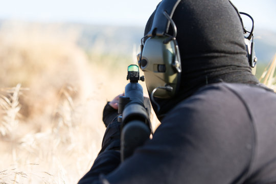 Man with rifle aiming in grassy field