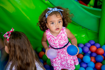 Happy little girl sitting in colourful balls