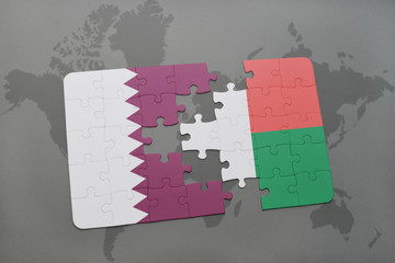 puzzle with the national flag of qatar and madagascar on a world map background.