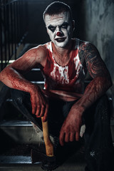 Fototapeta na wymiar Bloody clown-maniac with ax