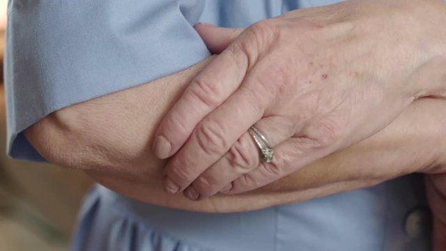 A senior woman - victim of physical elder abuse and domestic violence - uses her hand to cover a bruise on her arm. Shot in 4K UHD.