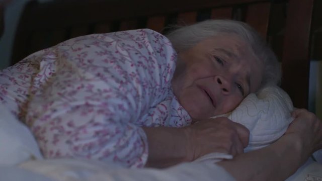 A senior woman in bed is shoved by an abusive man in an elder abuse, domestic violence scene. Shot in 4K UHD.