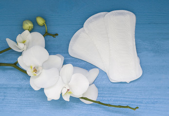 Sanitary pads and lilac orchid on blue wooden background