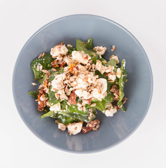 Spinach, dried tomatoes, feta cheese and sunflower seeds salad on a white background