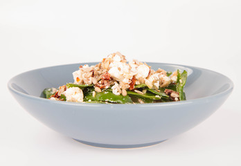 Spinach, dried tomatoes, feta cheese and sunflower seeds salad on a white background