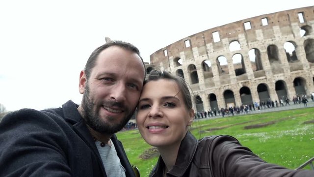 Happy couple taking selfie photo and recording video near Colosseum

