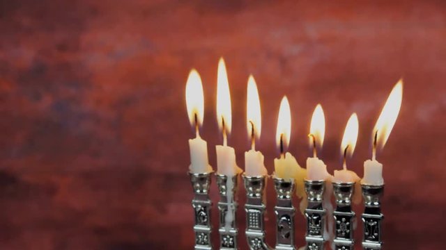 Chanukah candles all in a row. Bright, shiny multicolor candles for the Jewish holiday. All lit, isolated on a black background, horizontal view.
