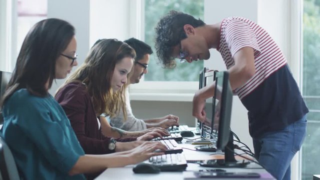 Group of Mixed Race Students are sitting in a Row and Working on Computers, one young Man pointing at Monitor. Shot on RED Cinema Camera in 4K (UHD).