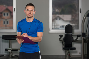 Personal Trainer Takes Notes On Clipboard