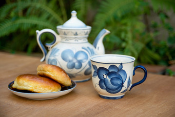 Tea set. Porcelain vintage cup and  teapot with cakes outdoors.