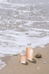 Bottles with oil essence and shell in the sea waves. Spa and wellness setting.