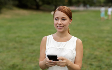 Caucasian woman in city park texting cell phone