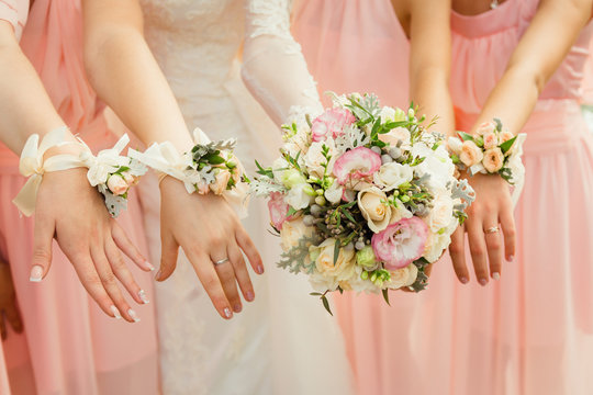 Bride and bridesmiads reach out their hands with flower bracelet