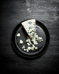 Aromatic cheese with blue mold on an old plate.