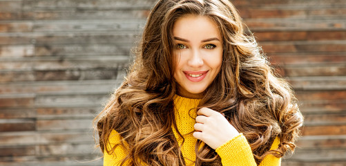 Beautiful smiling brunette woman with luxurious hair over wooden