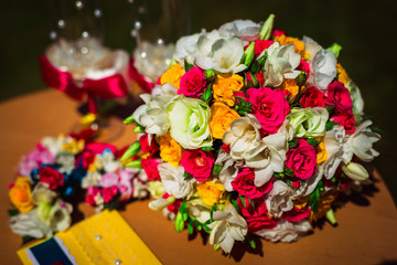 Bright wedding bouquet stands on the woodent table behind champa