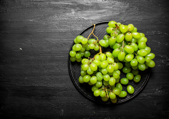 Branch of white grapes on a plate.