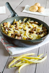 fried potatoes with mushrooms in a frying pan
