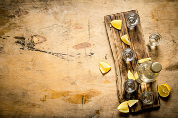 Bottle of vodka with shot glasses and lemon.