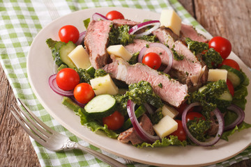 Sliced beef steak with a salad of cheese and vegetables close-up. horizontal

