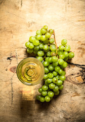 glass white wine with a branch ripe grapes.