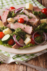 Salad with beef steak, cheese and vegetables dressed with chimichurri sauce closeup. vertical
