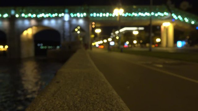 Blurred cyclist on urban embankment at night. 4K bokeh clip