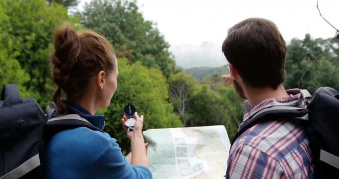 Rear view of hikers looking a map with a compass