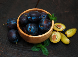 Bowl with  plums with green leaves