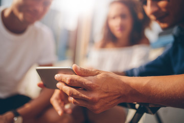 Young man showing mobile phone to friends