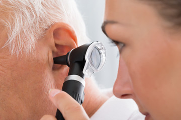 Female Doctor Examining Patient's Ear - obrazy, fototapety, plakaty