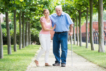 Woman With Her Disabled Father Standing In Park