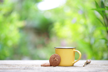 Yellow mug and cookie on wooden table