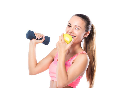 sporty woman with a dumbbell and eating an applea over white