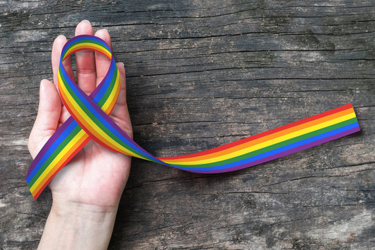 Rainbow ribbon awareness on human hand on grunge aged background, clipping path: Symbolic color logo icon for equal rights in same sex marriage: Social equality of LGBT community/ people concept