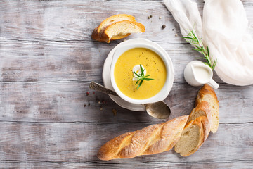 Delicious Vegetable cream soup in a white bowl and bread toasts on rustic wooden table, top view