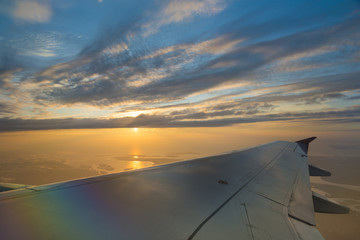 Fototapeta na wymiar Wing of an airplane flying above the sunset clouds